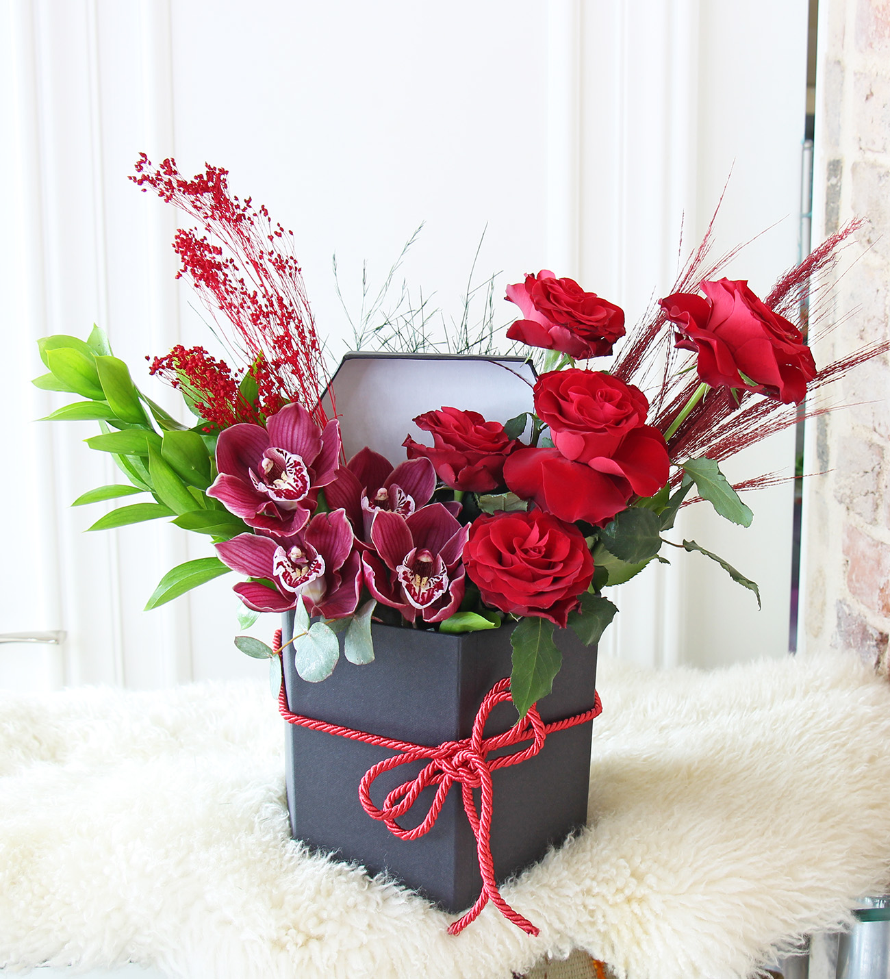 Siyah seri kutu kırmızı güller ve bordo simbidyum orkide aranjmanı