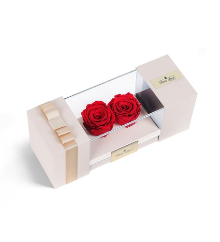 Two red everlasting roses in a beige box.