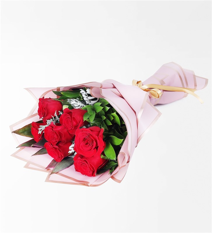 A bouquet of 7 red roses, cordyline, and wormwood in a pink-trimmed package.